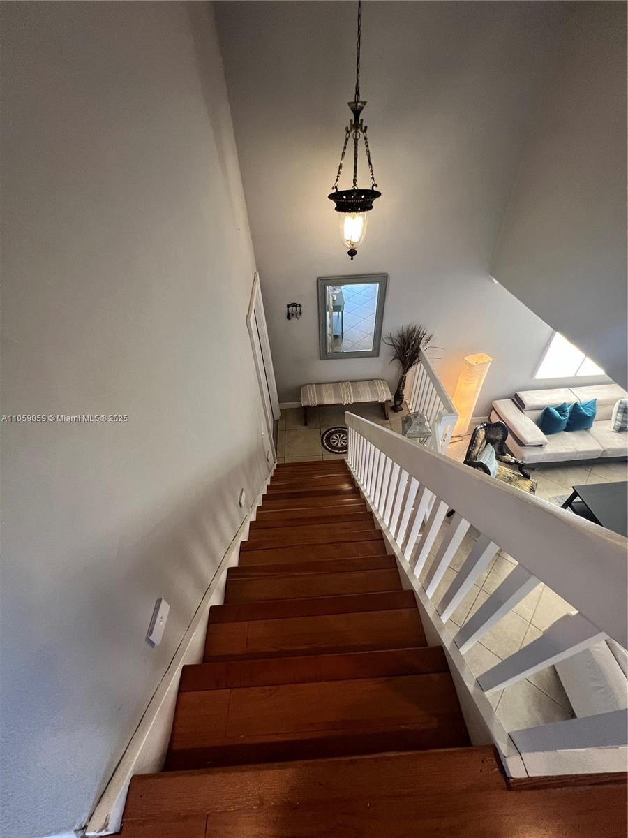 A wooden staircase with a white railing leads down to a living area and entryway — 4910 SW 149th Ct # 11B, Miami FL 33185, MIAMI, FL