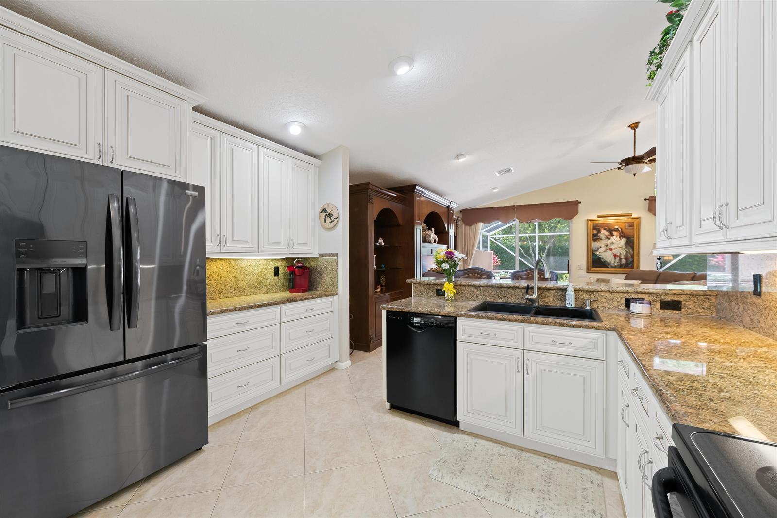 A kitchen features white cabinets, granite countertops, a black refrigerator, and a black dishwasher — 5185 Glenville Drive, Boynton Beach FL 33437, BOYNTON BEACH, FL