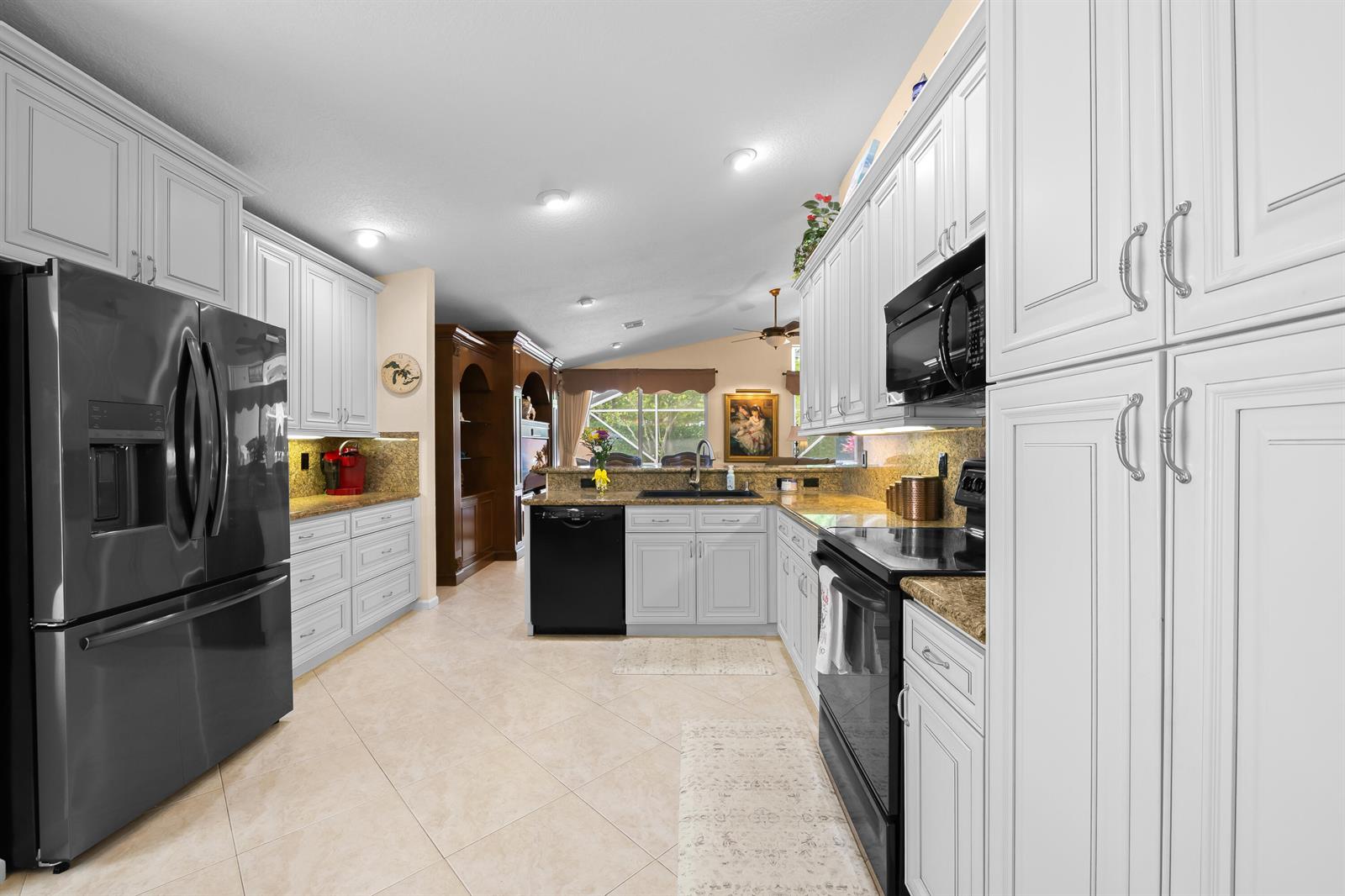 A kitchen features white cabinets, black appliances, granite countertops, and light-colored tile flooring — 5185 Glenville Drive, Boynton Beach FL 33437, BOYNTON BEACH, FL