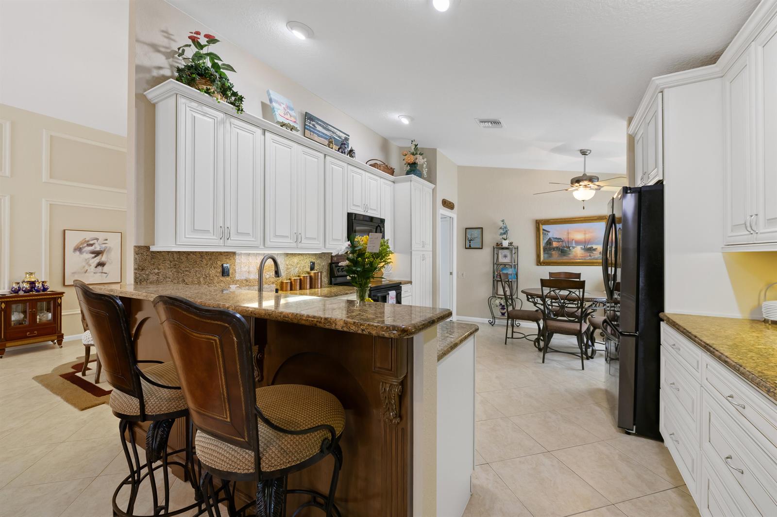 A kitchen features white cabinets, granite countertops, a breakfast bar, and an adjacent dining area — 5185 Glenville Drive, Boynton Beach FL 33437, BOYNTON BEACH, FL