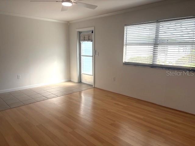 An empty room features light wood flooring, a tiled entryway, a ceiling fan, and blinds — 1901 ANDOVER WAY UNIT 38, SUN CITY CENTER, FL