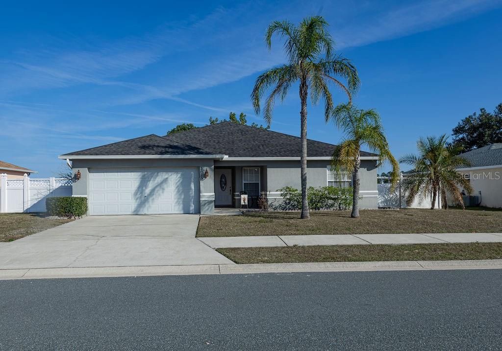 A single-story house with a gray exterior, a two-car garage, and two palm trees — 1015 HIGHLAND CREST CIRCLE, LAKE WALES, FL