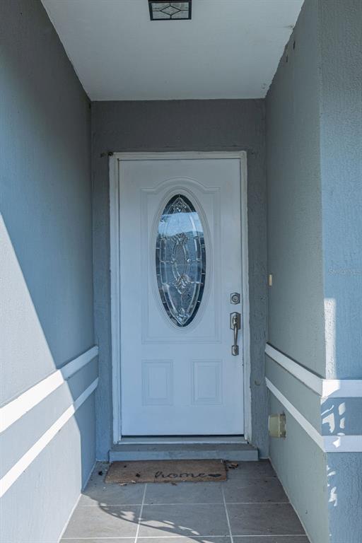 A white front door with an oval glass insert sits in a gray entryway — 1015 HIGHLAND CREST CIRCLE, LAKE WALES, FL