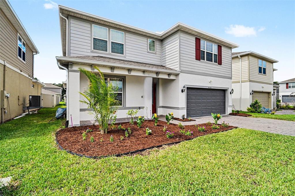 A two-story house with light gray siding, a dark garage door, and a front garden — 4305 FOGGY OAK LANE, SANFORD, FL