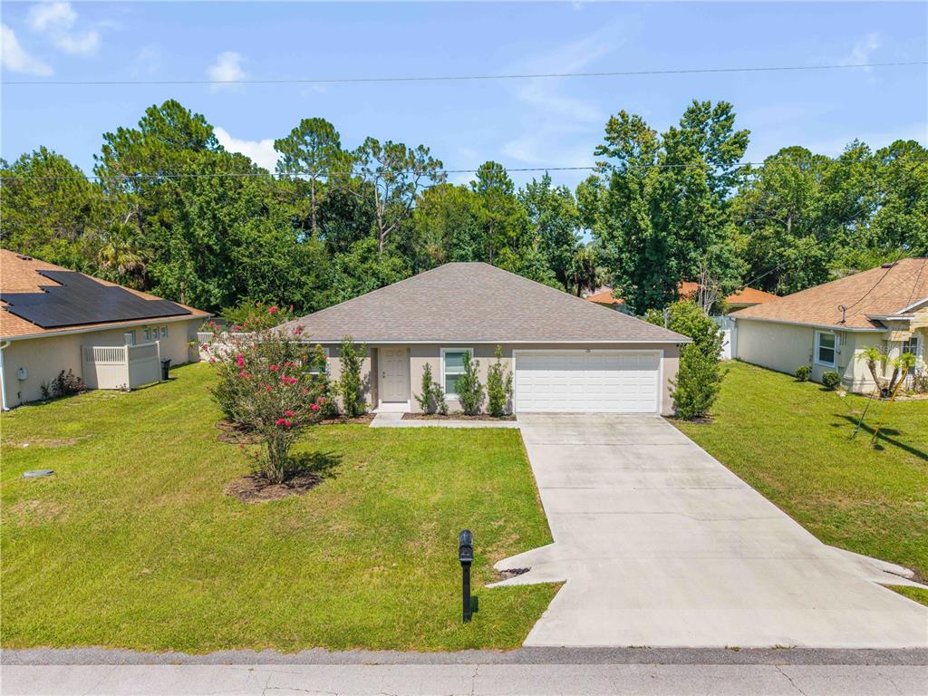 A single-story house with a beige exterior, a two-car garage, and a front lawn — 176 PINE GROVE DRIVE, PALM COAST, FL