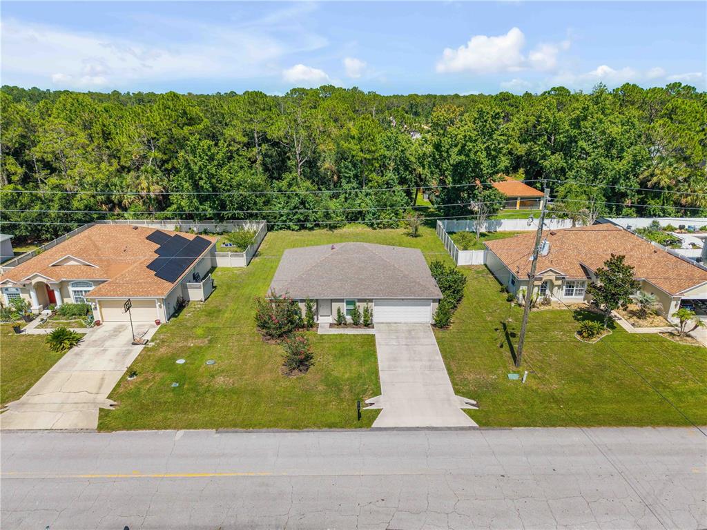 An aerial view shows a single-story house with a concrete driveway and a grassy yard — 176 PINE GROVE DRIVE, PALM COAST, FL