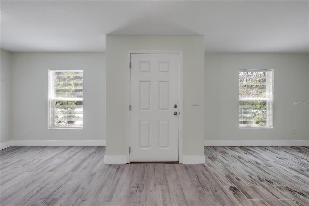 A room with light-colored walls, wood-look flooring, two windows, and a central white door — 176 PINE GROVE DRIVE, PALM COAST, FL