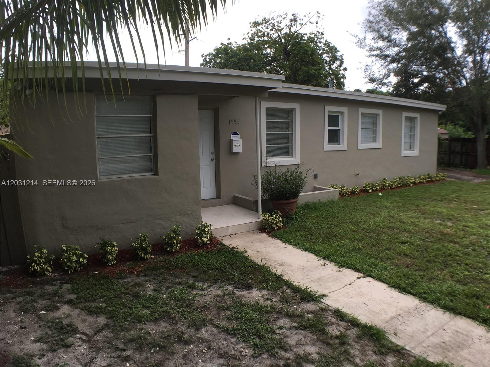 A single-story house with a beige exterior, white trim, and a small front walkway — 1594 NE 155th Ter, North Miami Beach FL 33162, NORTH MIAMI BEACH, FL