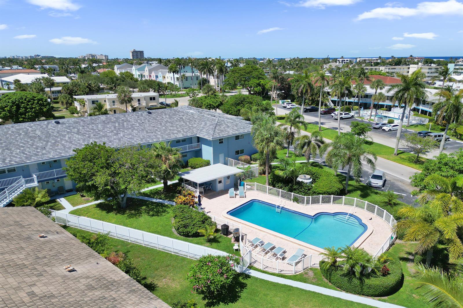 An aerial view shows a blue apartment building with a swimming pool and landscaped grounds — 2734 NE 27th Court # 22, Lighthouse Point FL 33064, LIGHTHOUSE POINT, FL