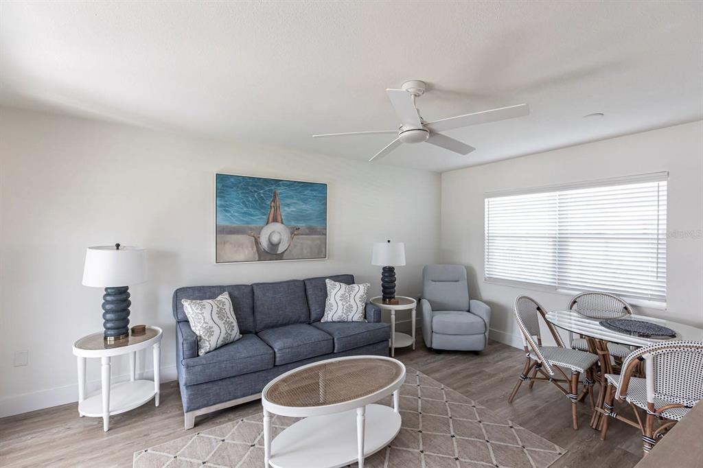 A living room features a blue sofa, a round coffee table, and a dining area — 6020 MIDNIGHT PASS ROAD UNIT 5, SARASOTA, FL