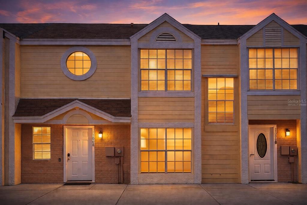 The exterior of two adjacent yellow townhouses features brick accents, white doors, and large windows — 11008 YORKSHIRE RIDGE COURT, ORLANDO, FL
