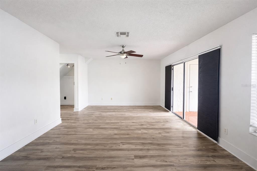 A bright living room features light wood-look flooring, white walls, and sliding glass patio doors — 11008 YORKSHIRE RIDGE COURT, ORLANDO, FL