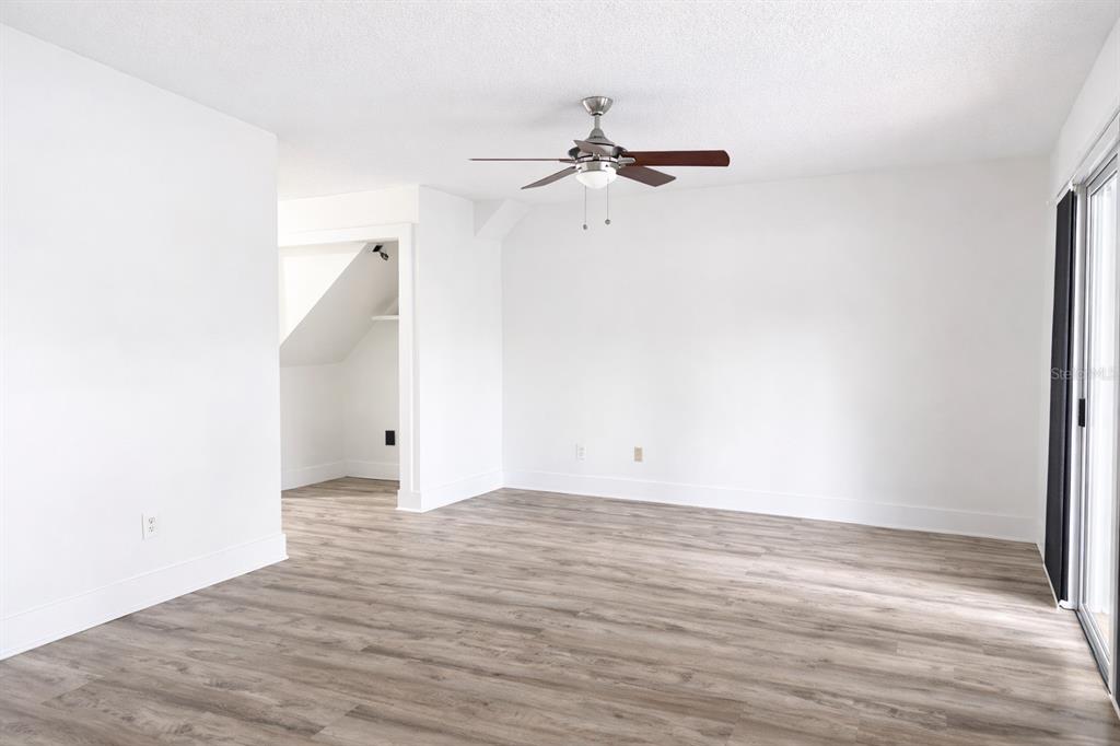 An empty room with white walls, wood-look flooring, a ceiling fan, and a recessed alcove — 11008 YORKSHIRE RIDGE COURT, ORLANDO, FL
