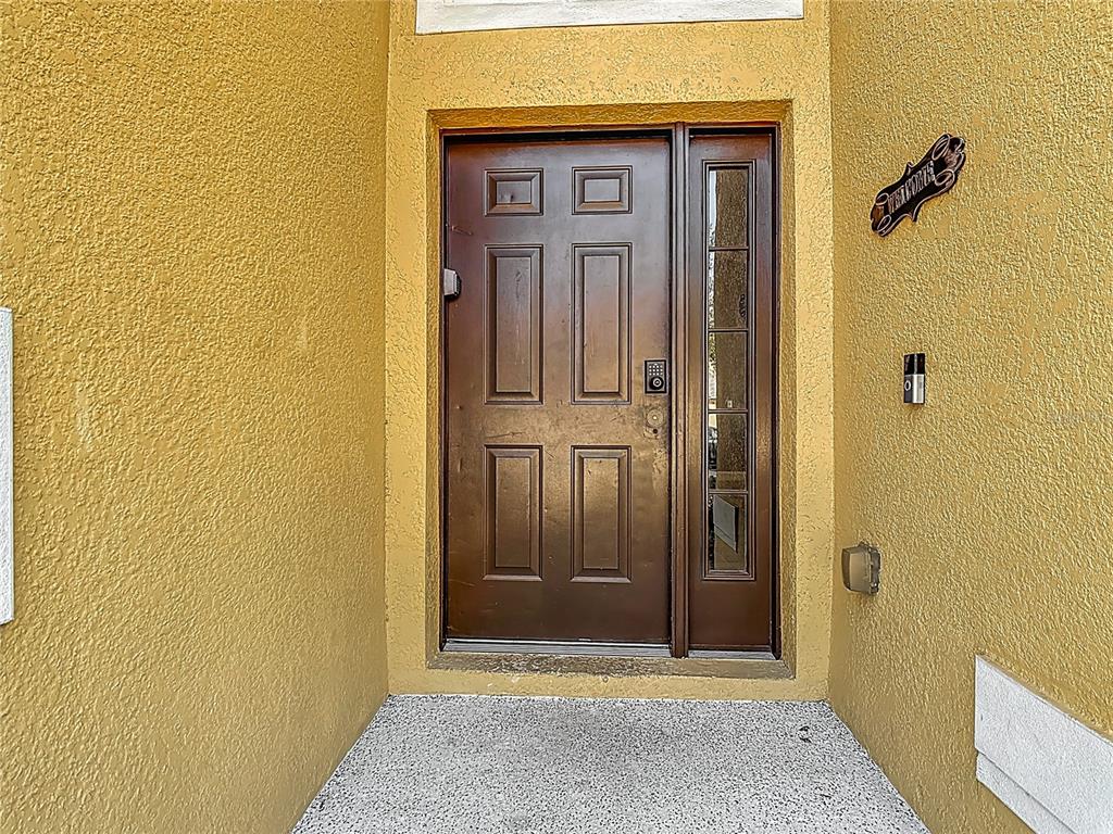 A brown front door with a side window is set into a yellow stucco entryway — 168 HIDEAWAY BEACH LANE, KISSIMMEE, FL