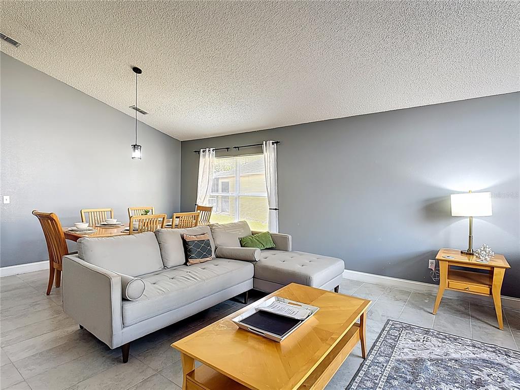 A living room and dining area feature gray walls, tile flooring, and a sectional sofa — 168 HIDEAWAY BEACH LANE, KISSIMMEE, FL
