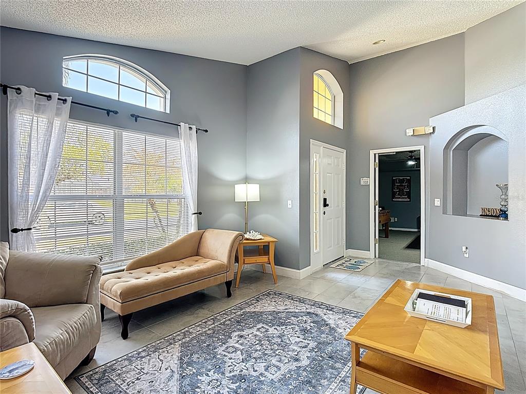 A living room features vaulted ceilings, tile flooring, a chaise lounge, and an arched wall niche — 168 HIDEAWAY BEACH LANE, KISSIMMEE, FL