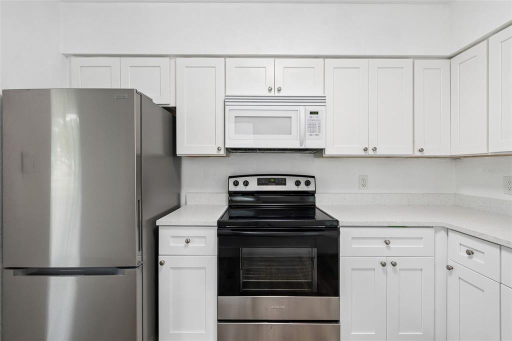 A kitchen featuring white cabinets, stainless steel appliances, and light-colored countertops — 2832 MIRIAM STREET S, ST PETERSBURG, FL