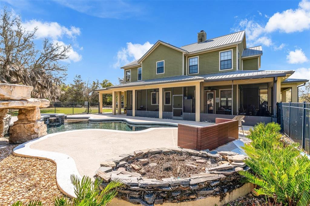 A two-story green house features a screened-in porch, a swimming pool, and a stone firepit — 326 ENTERPRISE OSTEEN ROAD, OSTEEN, FL