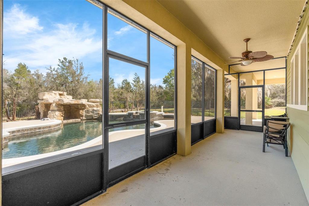A screened-in porch overlooks a swimming pool with a rock waterfall feature — 326 ENTERPRISE OSTEEN ROAD, OSTEEN, FL