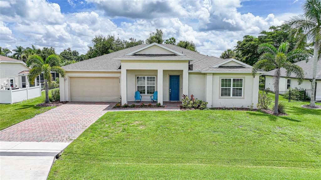 A single-story house with a beige stucco exterior, blue front door, and a paved driveway — 7442 S BLUE SAGE, PUNTA GORDA, FL