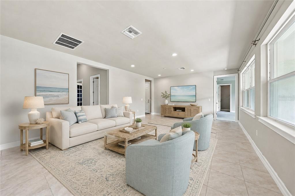 A bright living room features a beige sofa, two light blue armchairs, and tile flooring — 7442 S BLUE SAGE, PUNTA GORDA, FL