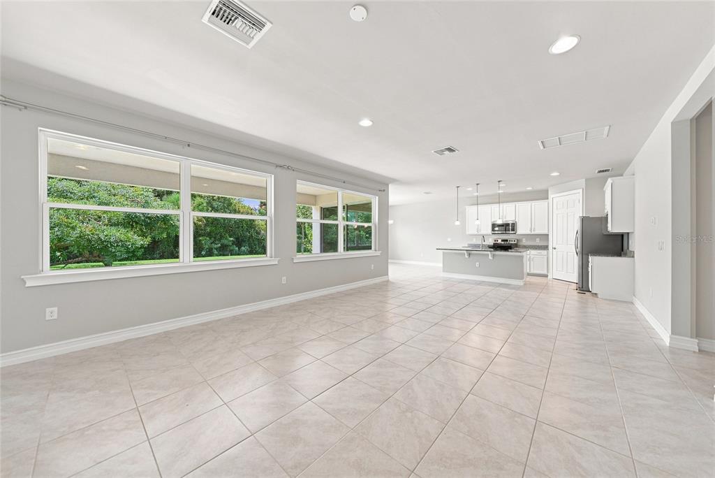 An open-concept living area with light tile flooring, white cabinets, and large windows — 7442 S BLUE SAGE, PUNTA GORDA, FL