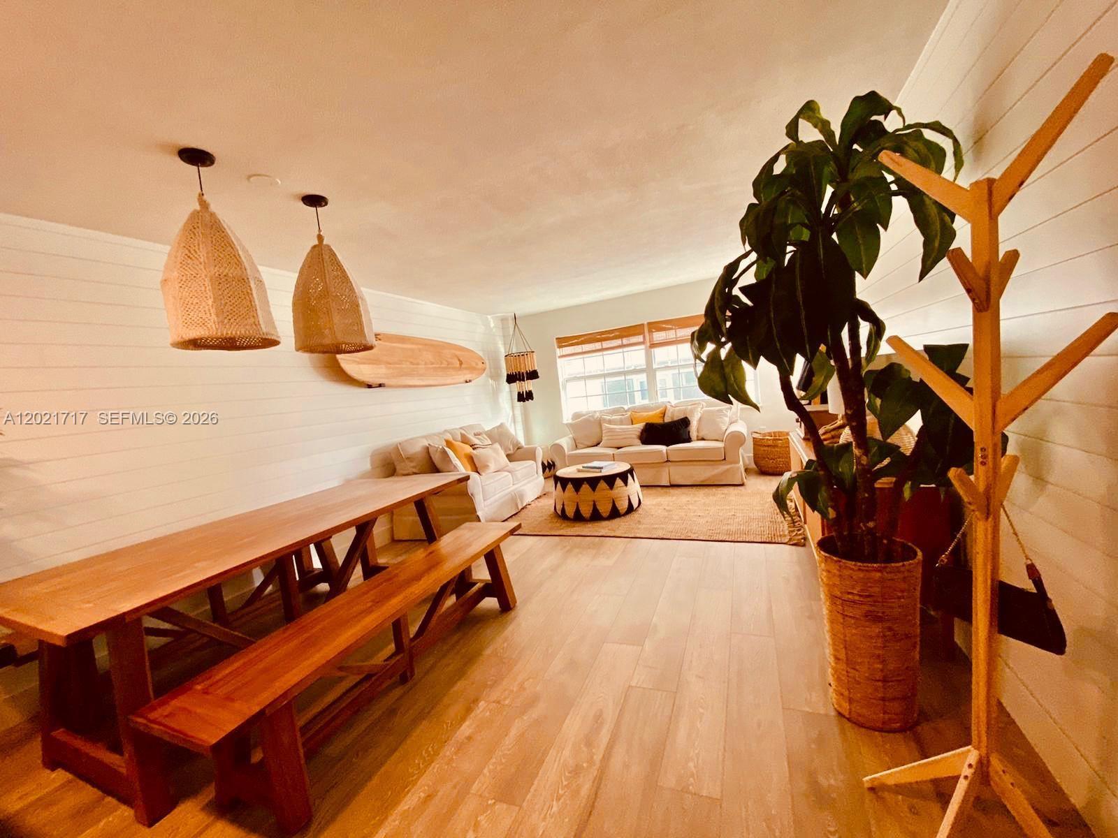 A living and dining area features white shiplap walls, wood flooring, and a surfboard decoration — 325 Ocean Dr # 408, Miami Beach FL 33139, MIAMI BEACH, FL