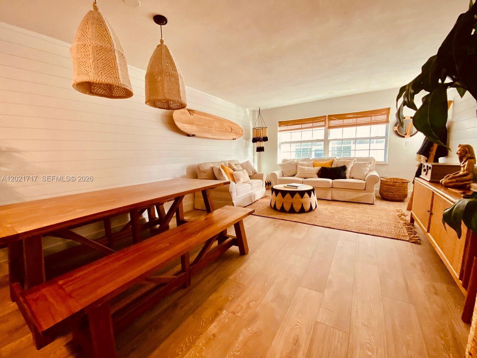 A living and dining area features wood flooring, shiplap walls, and a surfboard wall decoration — 325 Ocean Dr # 408, Miami Beach FL 33139, MIAMI BEACH, FL
