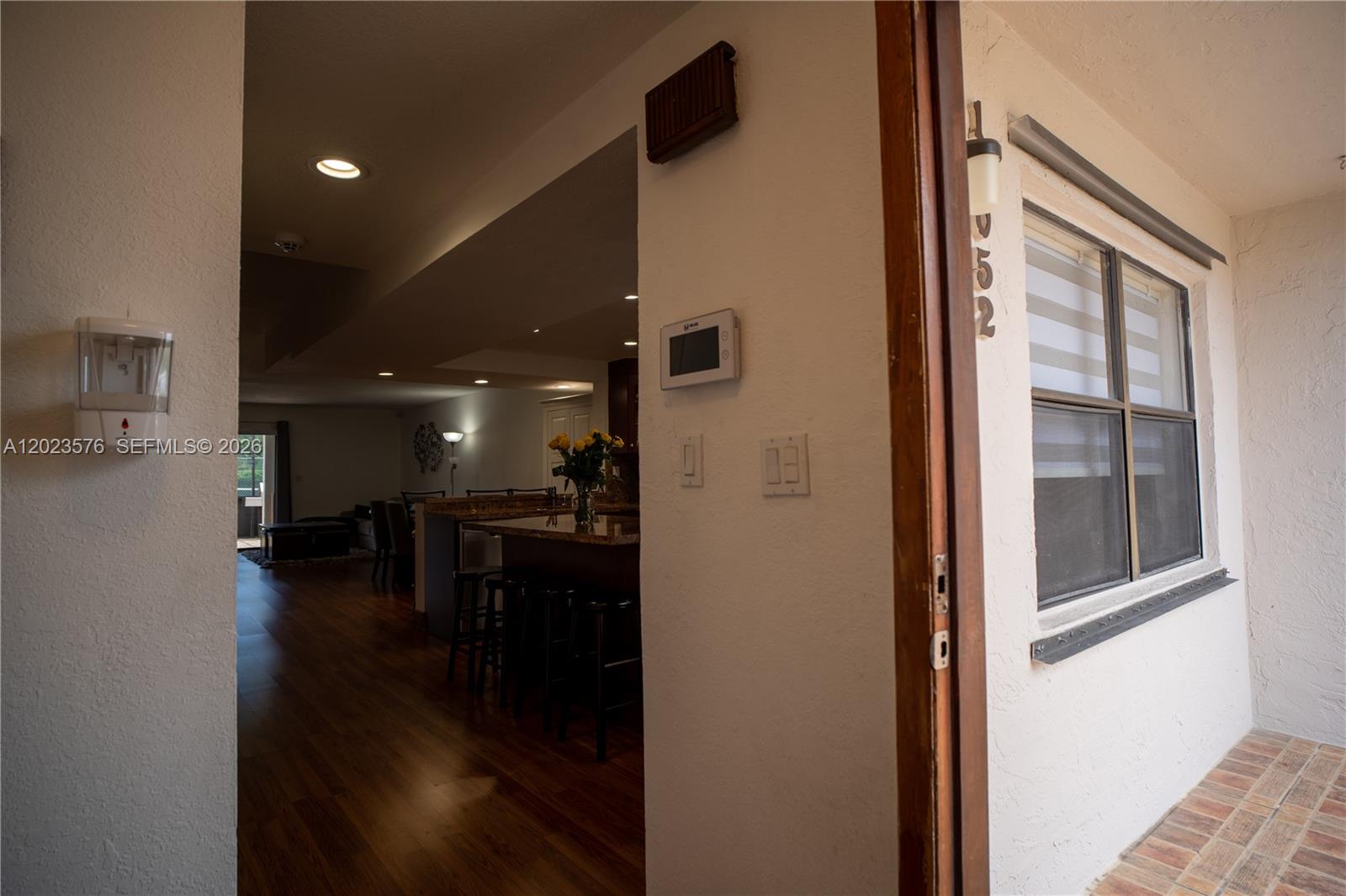 An open doorway reveals a kitchen with a granite island and hardwood flooring — 10052 NW 41st St # 5, Doral FL 33178, DORAL, FL