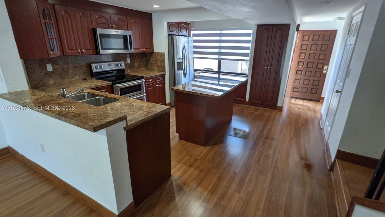 A kitchen features dark wood cabinets, granite countertops, stainless steel appliances, and wood-look flooring — 10052 NW 41st St # 5, Doral FL 33178, DORAL, FL