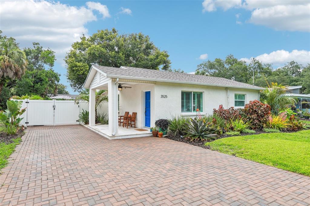 A single-story house with a white stucco exterior, blue door, and a brick-paved driveway — 3525 W PAUL AVENUE, TAMPA, FL