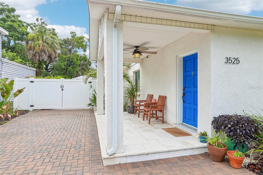 A covered front porch features a bright blue door, tiled flooring, and two wooden chairs — 3525 W PAUL AVENUE, TAMPA, FL