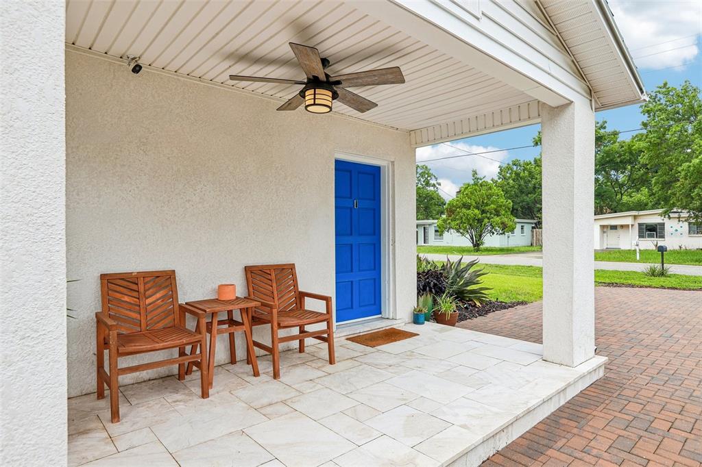 A covered front porch features a blue door, two wooden chairs, and a ceiling fan — 3525 W PAUL AVENUE, TAMPA, FL