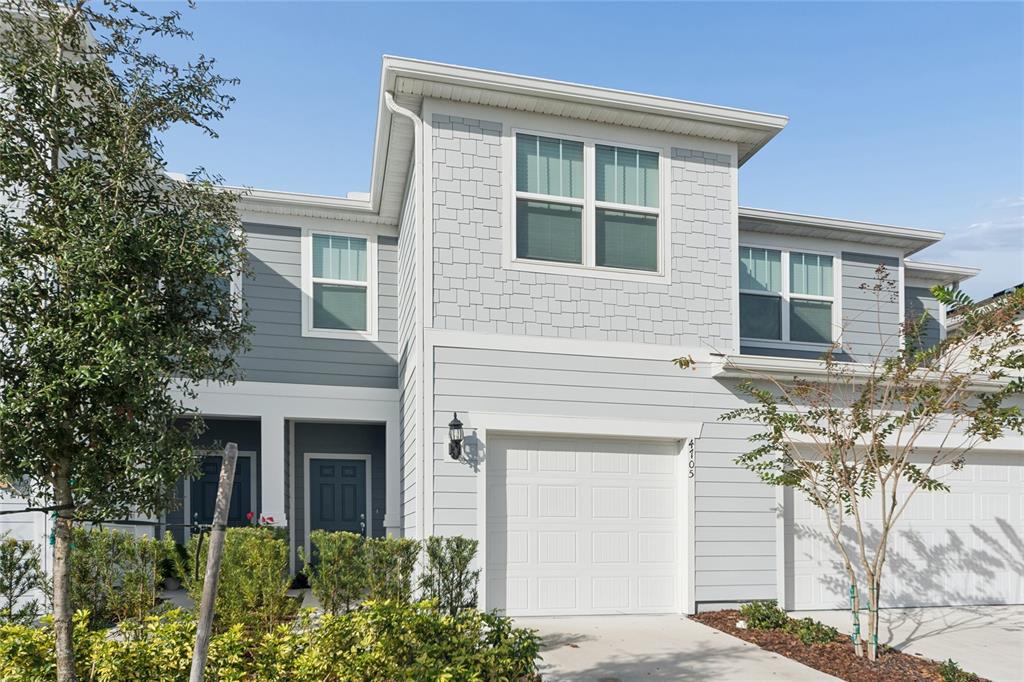 A two-story townhouse with gray siding, a white garage door, and a small front yard — 4705 SPARKLING SHELL AVENUE, KISSIMMEE, FL