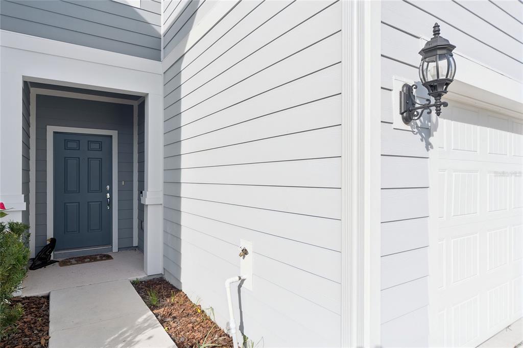 The exterior of a house features a blue front door, light siding, and a garage — 4705 SPARKLING SHELL AVENUE, KISSIMMEE, FL