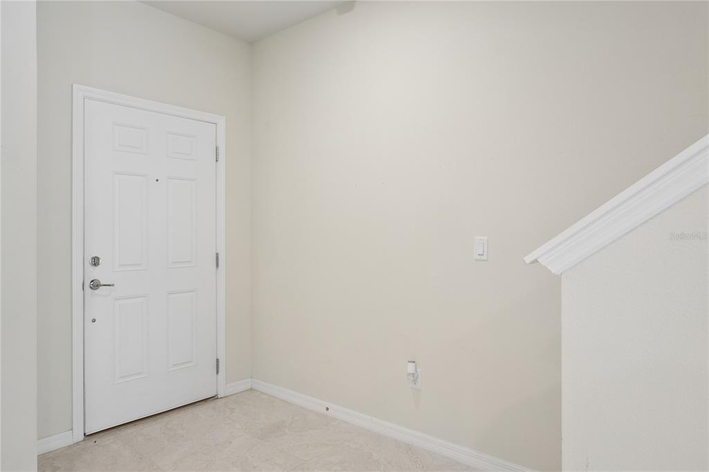 An entryway features a white front door, light-colored tile flooring, and a staircase railing — 4705 SPARKLING SHELL AVENUE, KISSIMMEE, FL