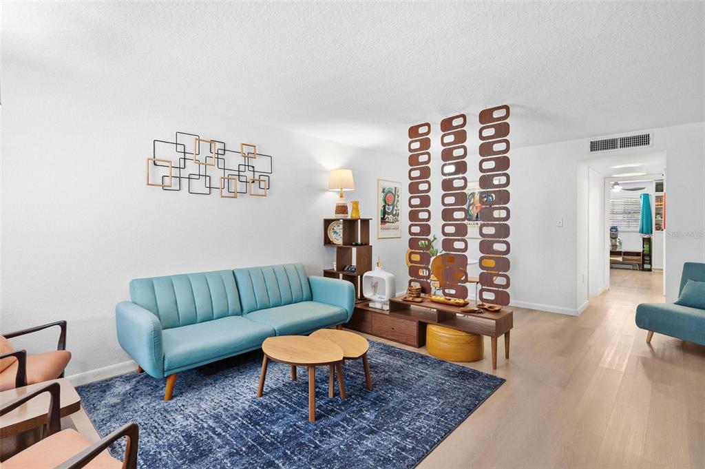 A living room features a blue sofa, a patterned room divider, and light wood flooring — 1112 W MAIN STREET UNIT C4, LEESBURG, FL