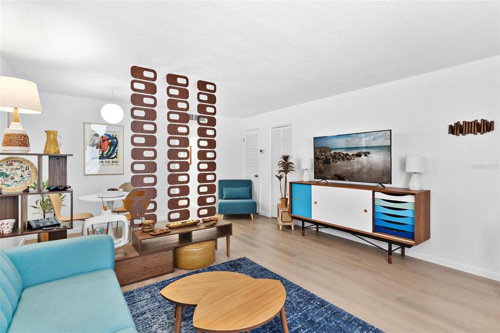 A living room features a blue sofa, a mid-century modern media console, and a room divider — 1112 W MAIN STREET UNIT C4, LEESBURG, FL