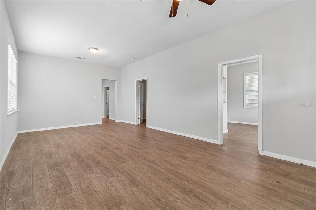 An empty room with light gray walls, wood-look flooring, and three doorways — 1522 E 21ST AVENUE, TAMPA, FL