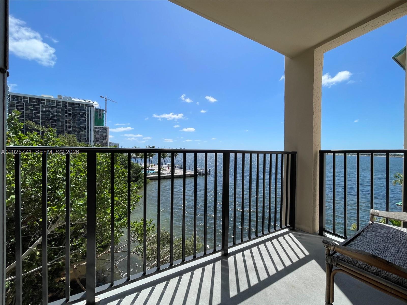 A balcony with a black metal railing overlooks a bay with a distant building — 2201 Brickell Ave # 73, Miami FL 33129, MIAMI, FL