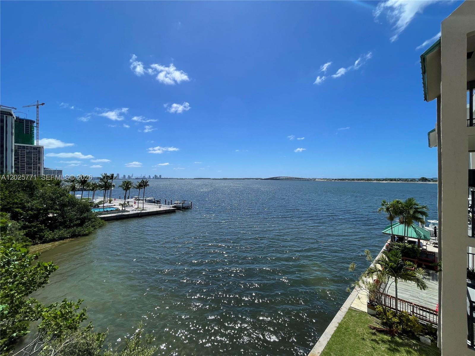 A view from a balcony overlooking a bay with a dock and distant bridge — 2201 Brickell Ave # 73, Miami FL 33129, MIAMI, FL
