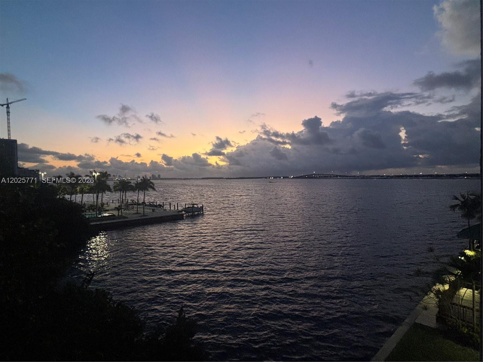 A sunset view over a body of water with a pier, palm trees, and bridge — 2201 Brickell Ave # 73, Miami FL 33129, MIAMI, FL