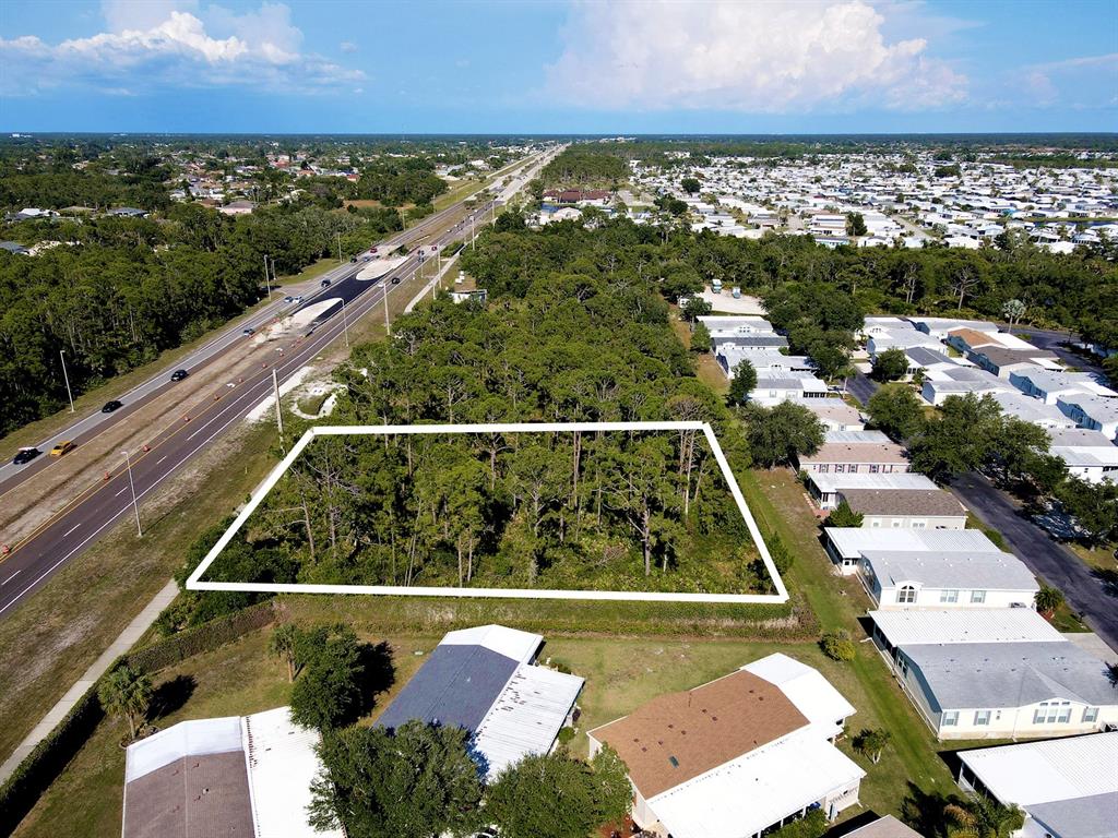 An aerial view shows a rectangular wooded lot bordered by a highway and residential homes — Lots 1-4 TAMIAMI TRAIL, NORTH PORT, FL