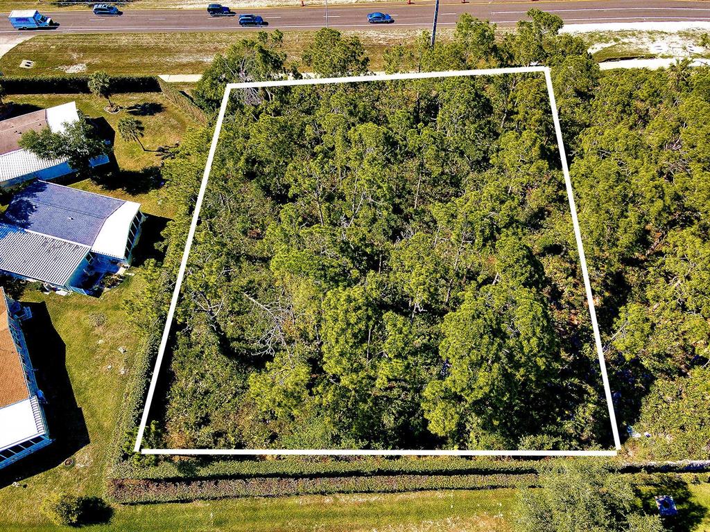 An aerial view shows a rectangular, tree-covered vacant lot outlined in white — Lots 1-4 TAMIAMI TRAIL, NORTH PORT, FL