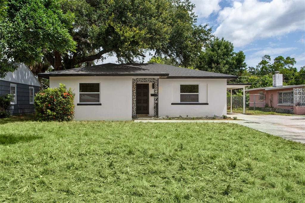 A white single-story house with a dark roof, a front door, and a grassy lawn — 1421 26TH AVENUE S, ST PETERSBURG, FL