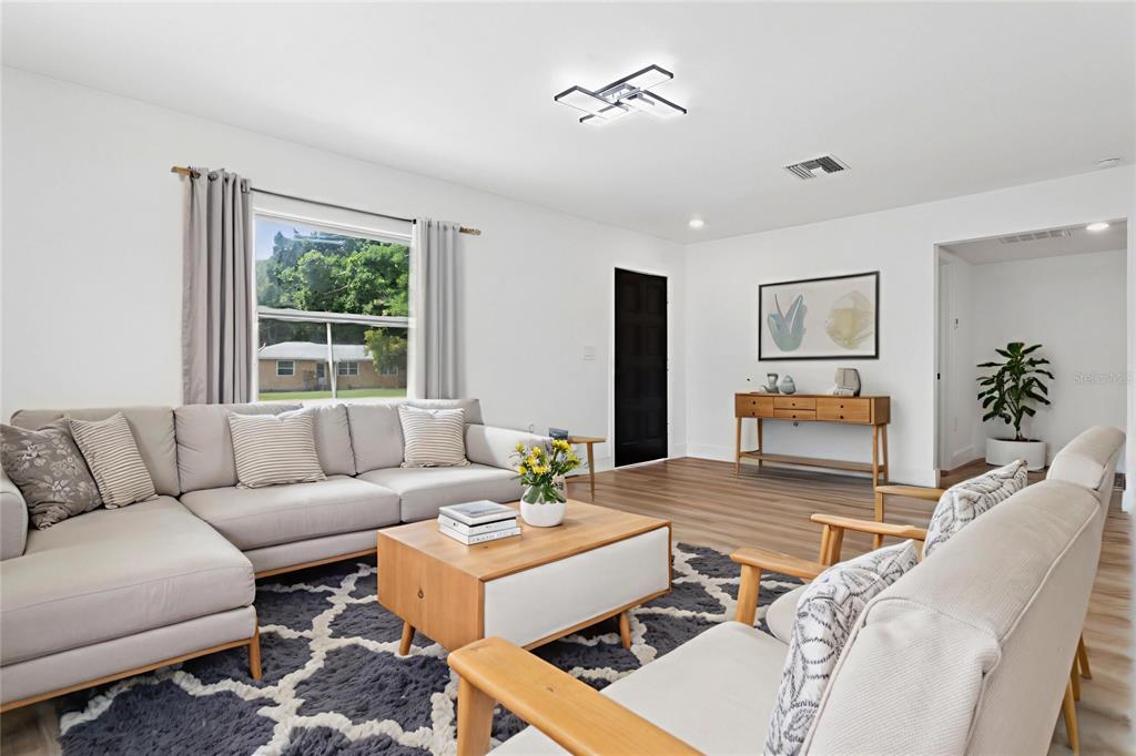 A living room features a grey sectional sofa, a wooden coffee table, and wood-look flooring — 1421 26TH AVENUE S, ST PETERSBURG, FL