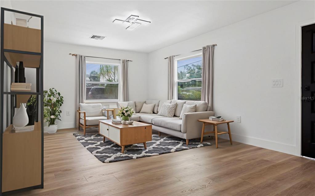 A living room features light wood flooring, a sectional sofa, a coffee table, and two windows — 1421 26TH AVENUE S, ST PETERSBURG, FL