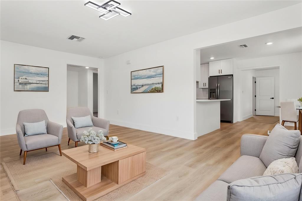 A living room with light wood floors, two armchairs, a sofa, and an open kitchen — 1421 26TH AVENUE S, ST PETERSBURG, FL