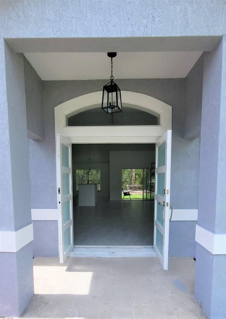 A view through open double doors into a bright, empty home with a kitchen island — 14429 36th Avenue, FL 34491, FL