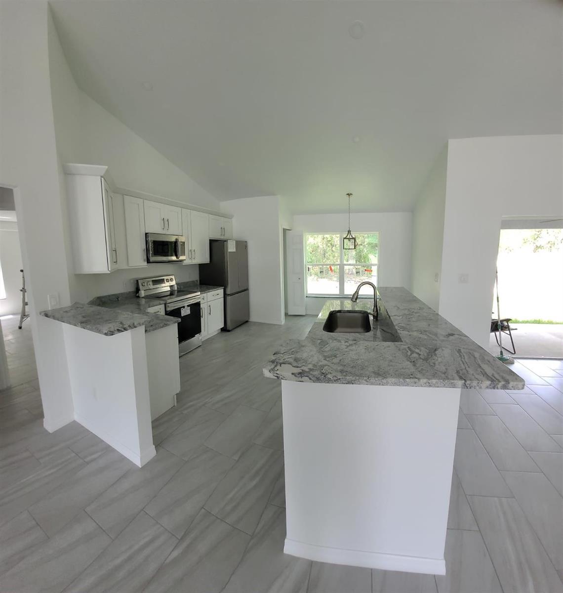 A modern kitchen features white cabinets, granite countertops, stainless steel appliances, and light tile flooring — 14429 36th Avenue, FL 34491, FL